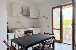 A modern kitchen with white cabinets, a black dining table, and a sliding glass door leading to an outdoor area. - M135 - Marcelli, three room apartment with porch 150meters from the sea (Marcelli)