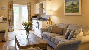 A living room with a sofa, a coffee table, a lamp, and a painting on the wall. - Craigmore View-UK34220 (Aberfoyle)