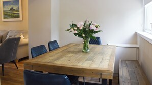 A dining area with a wooden table, chairs, and a vase of flowers. - Craigmore View-UK34220 (Aberfoyle)