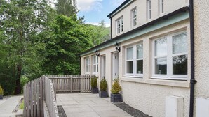 A two-story building with a light-colored exterior, multiple windows, and a wooden fence. - Craigmore View-UK34220 (Aberfoyle)