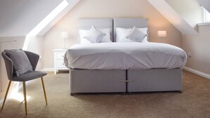 A bedroom with a large bed, a nightstand, a chair, and a ceiling light. - Craigmore View-UK34220 (Aberfoyle)
