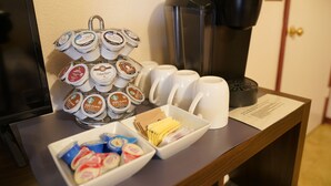 Un coin café équipé d’une machine à café, d’un plateau de dosettes de café et d’un bol de collations.