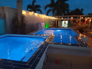 En pool med vandeffekter og lyskæder i skumringen.