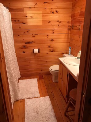 Un baño con paneles de madera, un inodoro, un lavamanos y un perchero para toallas.