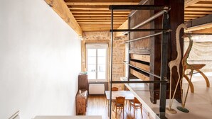 A staircase with a metal handrail leading to a dining area with wooden chairs and a table.