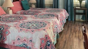 Ein Schlafzimmer mit einem großen Bett, einem Deckenventilator und einem Fenster mit Vorhängen.