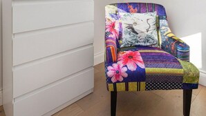 Una habitación con tragaluces, un aparador blanco y una silla colorida.