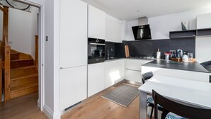 Una cocina moderna con armarios blancos, una estufa negra y una escalera de madera.