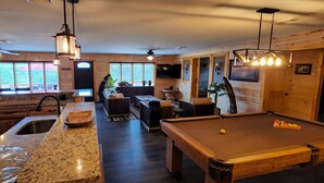 A spacious room with a pool table, a bar area, and a seating area with a couch and chairs. - Beautiful Home with Lake Views 4/2, Beautiful Home with Lake Views 4/2 - Resort Access for Fee (Lake George)