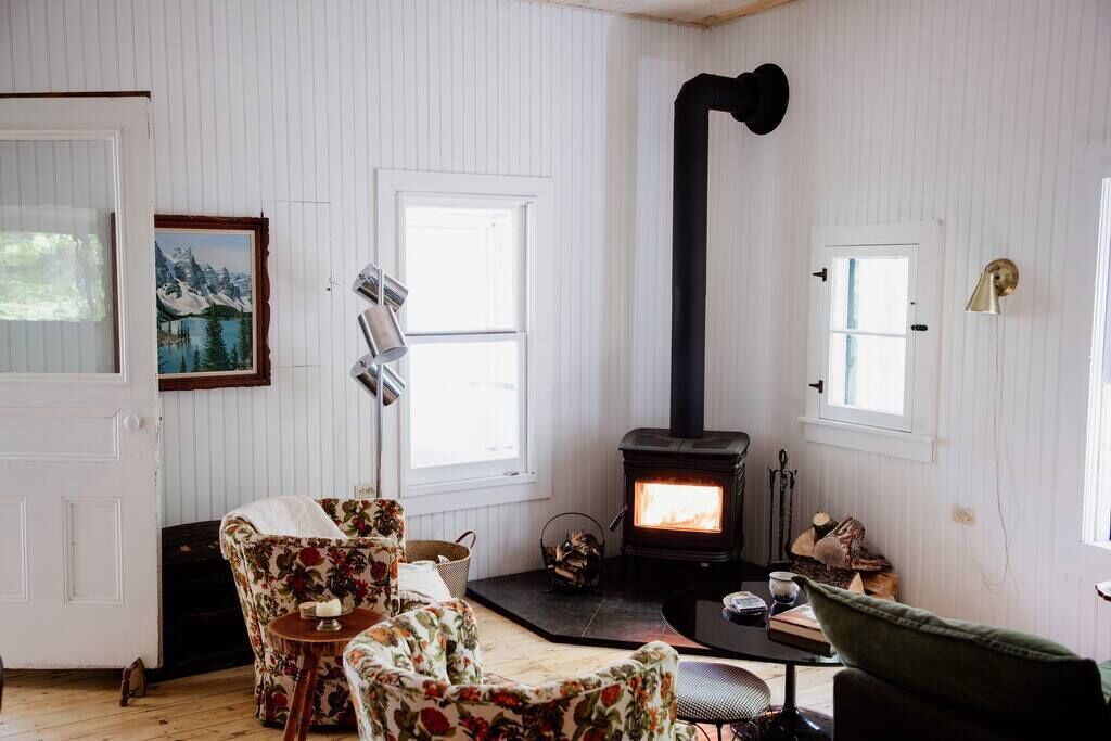 A cozy room with a fireplace, floral chairs, and a painting on the wall.