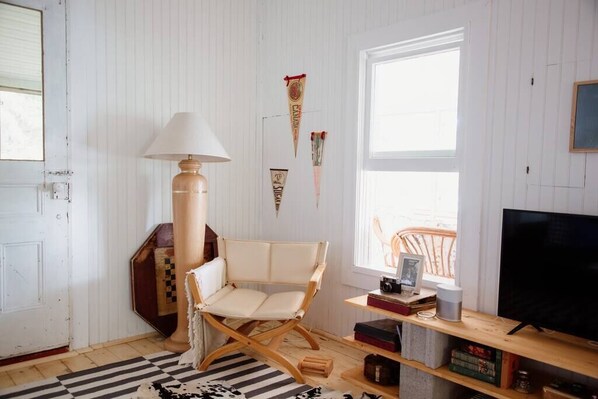 A room with a large window, a television, a lamp, and a chair. - The Dance Hall Cottage on Charleston Lake (Athens)