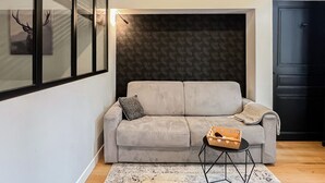 Una sala moderna con un sofá gris, una mesita auxiliar y un papel tapiz estampado.