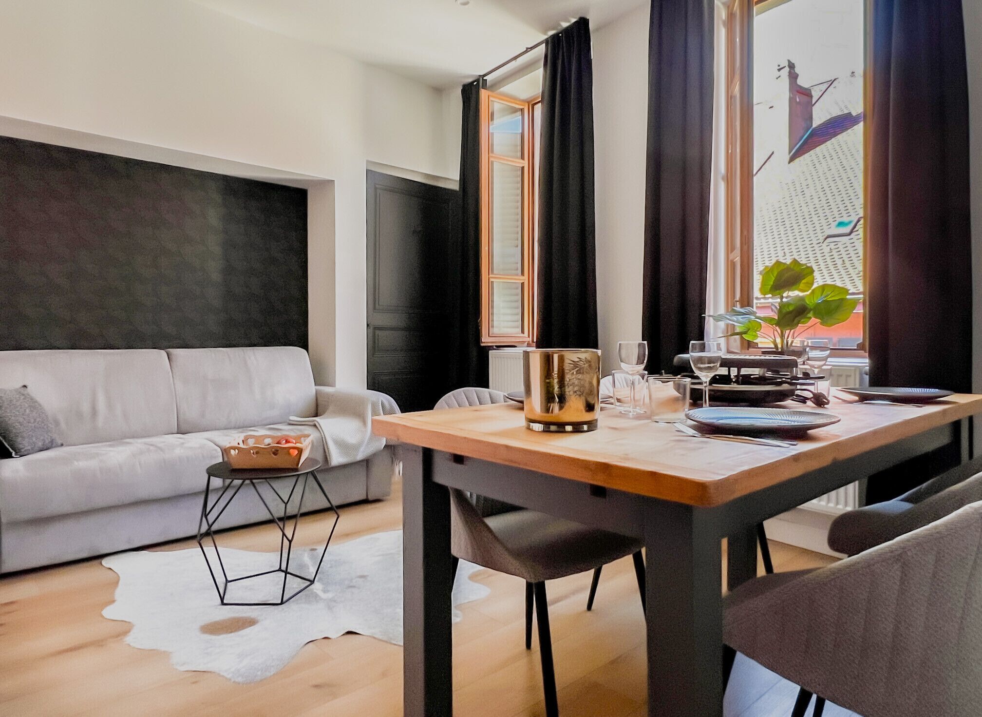 Un salon moderne comprenant un canapé, une table à manger avec des chaises, une table basse et une fenêtre avec des rideaux.