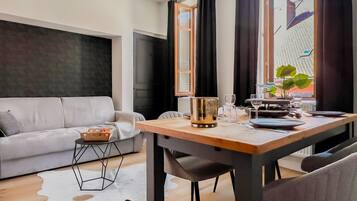 Un salon moderne comprenant un canapé, une table à manger avec des chaises, une table basse et une fenêtre avec des rideaux.
