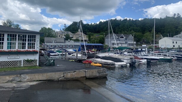 Un puerto deportivo con barcos amarrados, un edificio con la leyenda "APPAREL" y un letrero que indica "ABIERTO".