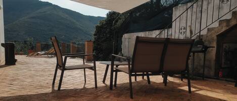 An outdoor patio with brick flooring, two chairs, a table, and a white canopy.