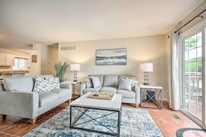 A living room with a grey sofa, a coffee table, and a painting on the wall. - 2 Decks, Dock, Fire Pit! Waterfront Lake Ozark Gem (Lake Ozark)