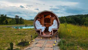 Two people in white robes sitting inside a wooden structure with a view of a natural landscape and a body of water. - Rustic Hobbit Inspired Hocking Hills State Park 3 mi away Hot Tub Pet Friendly  (Creola)