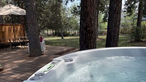 Ein Whirlpool auf einer Holzterrasse mit einem Holzzaun und Stühlen im Hintergrund.