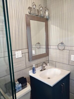Un baño moderno con un espejo grande, un lavamanos y un perchero para toallas.