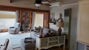 A cozy living room with a fireplace, a ceiling fan, and a comfortable seating area. - Cozy Lake Cabin With Beautiful View! (Gravois Mills)