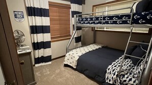 A bunk bed room with a ceiling fan, striped curtains, a private dock sign, and a fan on a small table. - Cozy Lake Cabin With Beautiful View! (Gravois Mills)