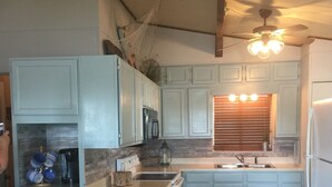 A kitchen with light blue cabinets, a central island, a built-in oven, a sink, and a ceiling fan. - Cozy Lake Cabin With Beautiful View! (Gravois Mills)