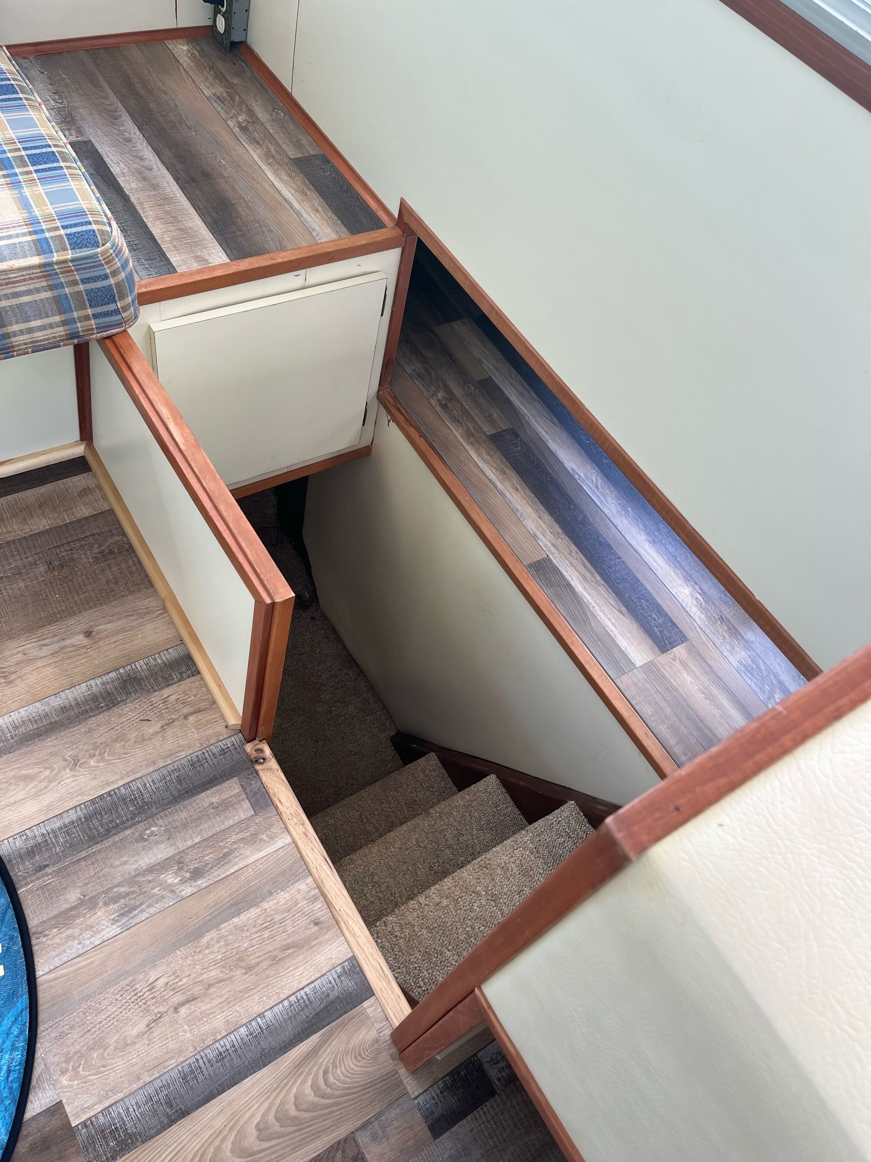 A compact kitchen with a wooden countertop, a white cabinet, and a staircase leading to a lower level.