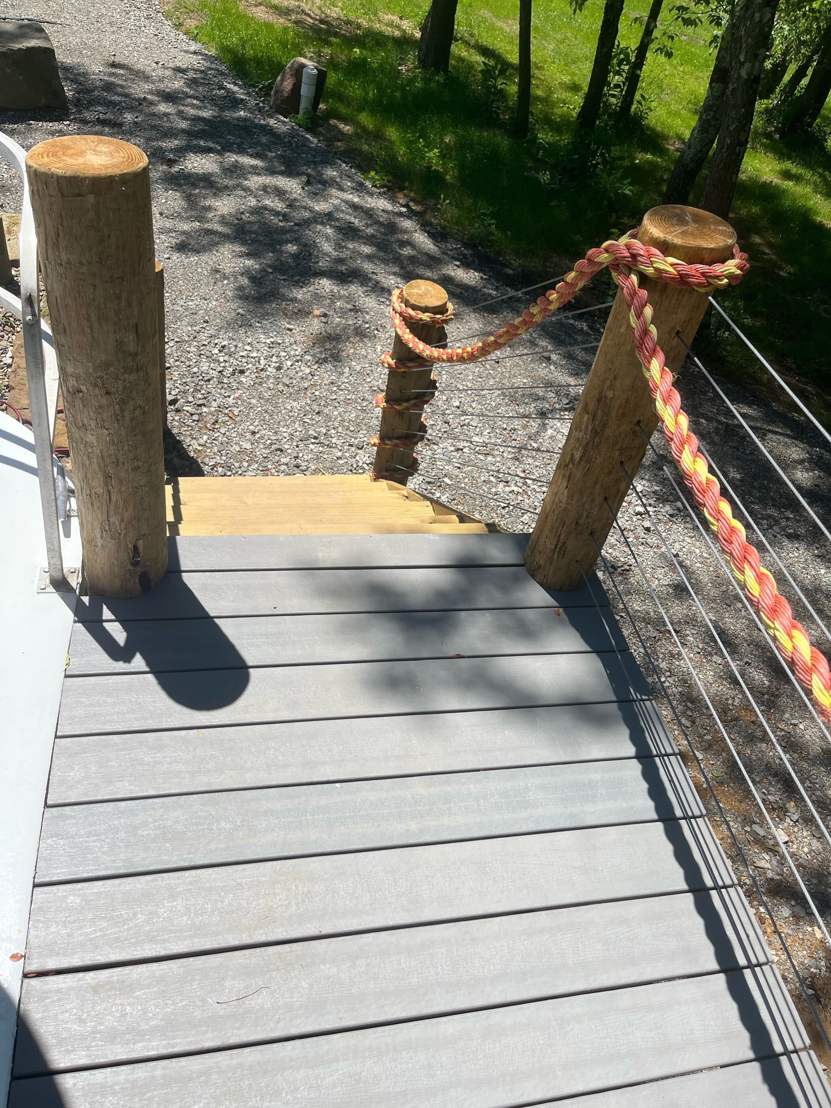 Une terrasse en bois avec une barrière en corde et un poteau en bois.