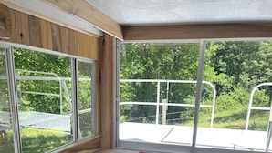 Cocina compacta con armarios de madera, un refrigerador negro y una ventana con vistas a un paisaje verde.