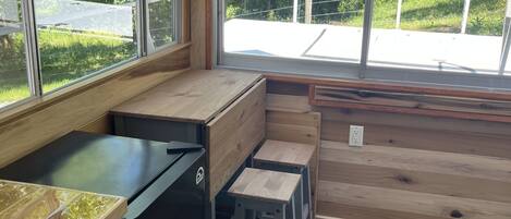 Een compacte keuken met houten kastjes, een zwarte koelkast en een raam met uitzicht op een groen landschap.