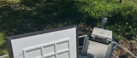 A portable hot tub with a control panel and a water pump, set up outdoors with a wooden fence and greenery in the background.