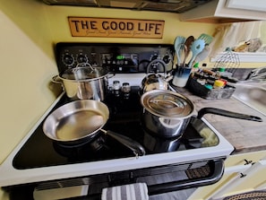 Une cuisine équipée d’une cuisinière, de casseroles et d’un panneau sur lequel on peut lire : « LA BELLE VIE ».