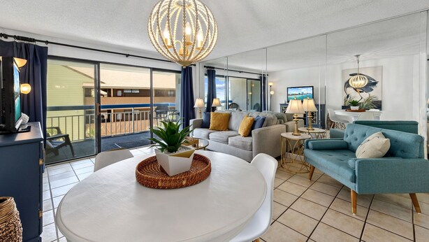 A modern living room with a round dining table, sofas, and a large chandelier. - ~Gorgeous~ Ocean View King Suite in Cabana Row~ (Myrtle Beach)