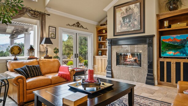 A cozy living room with a fireplace, leather sofa, and a television. - A Taste of Tuscany -Just 5 Minutes to Golf and Wine Tasting  (Fallbrook)