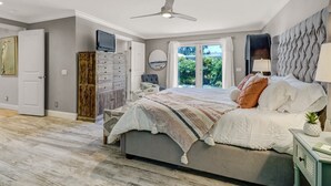 A bedroom with a bed, a ceiling fan, a television, a wardrobe, and a view of greenery outside. - Coastal Soul House in the heart of Naples (Naples)