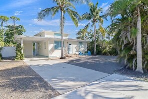 A single-story house with a covered porch, palm trees, and a clear sky.
