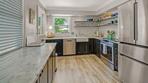A modern kitchen with stainless steel appliances, a marble countertop, and a window with a view of greenery. - Coastal Soul House in the heart of Naples (Naples)