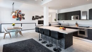 Eine moderne Küche mit einer zentralen Kochinsel, Barhocker und einem Essbereich mit Tisch und Stühlen.