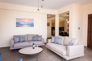 Uma sala de estar com dois sofás, uma mesa de centro e um quadro na parede.