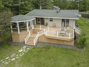 A two-story house with a covered deck, a staircase, and outdoor seating.