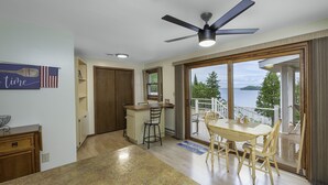 A kitchen with a dining area, a ceiling fan, and a view of a lake through large sliding glass doors.