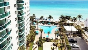 A high-rise hotel with a pool area, palm trees, and a view of the ocean. - Apt w/2 Queen Beds and Canal View at Tides (Hollywood)