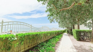 A pathway lined with greenery and a white fence leading to a beach. - Apt w/2 Queen Beds and Canal View at Tides (Hollywood)