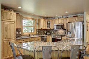 A modern kitchen with granite countertops, stainless steel appliances, and wooden cabinetry.