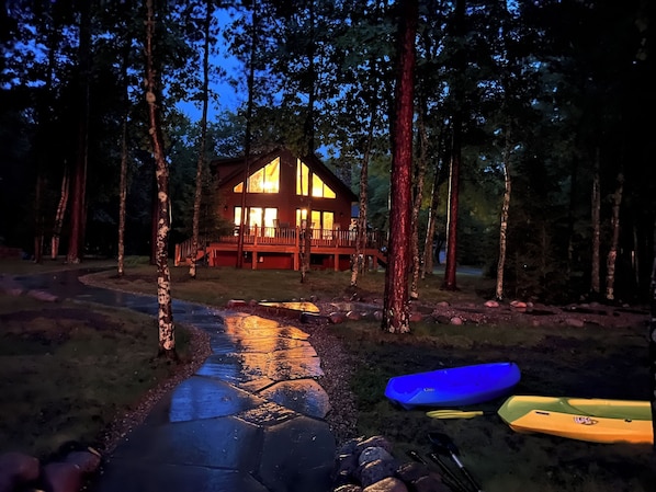 Eine Lodge mit einer Holterrasse und großen Fenstern, umgeben von Bäumen.