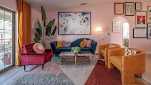 A living room with a sofa, two armchairs, a coffee table, and a large abstract painting on the wall. - ★Hot tub under the stars★ 4-King Beds, Cowboy Pool, Game Room, Fire Pit, JTNP (Twentynine Palms)