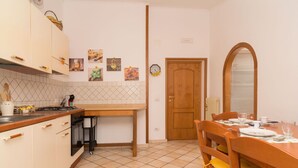 A kitchen with a tiled floor, wooden cabinets, a dining table with chairs, and a clock on the wall. - Nice apartment for 2 guests with A/C and terrace (Sorrento)