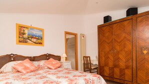 A bedroom with a bed, a wooden wardrobe, a desk, and a painting on the wall. - Nice apartment for 2 guests with A/C and terrace (Sorrento)