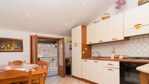 A compact kitchen with white cabinets, a wooden dining table, and a tiled floor. - Nice apartment for 2 guests with A/C and terrace (Sorrento)